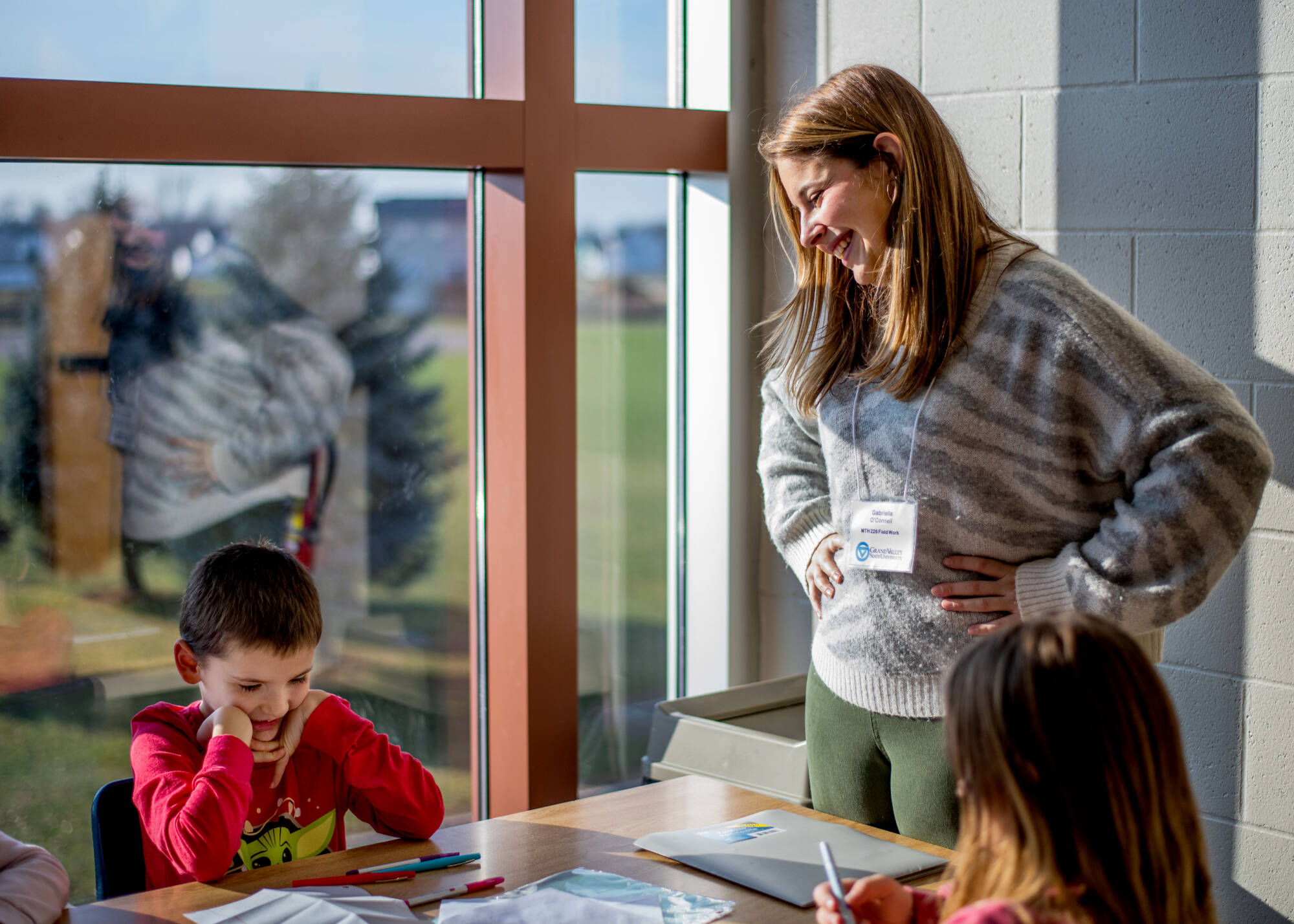 A GVSU student working with two elementary-aged students